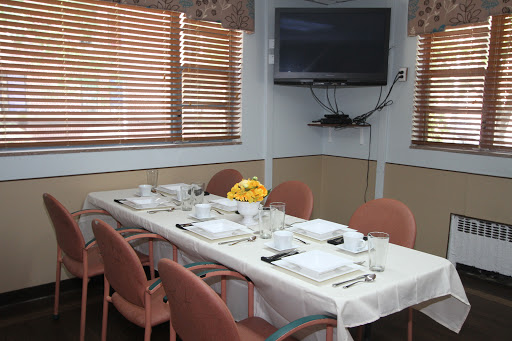 A beautifully set dining table in a restaurant, featuring a television and natural light from wooden blinds.