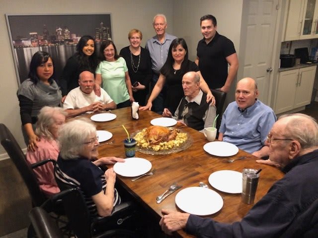 A family gathering around a dinner table with turkey as the centerpiece.