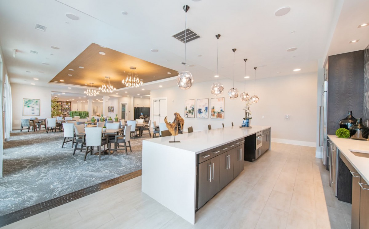 A modern, luxurious kitchen and dining area featuring an island counter, elegant chandeliers, and open space design.