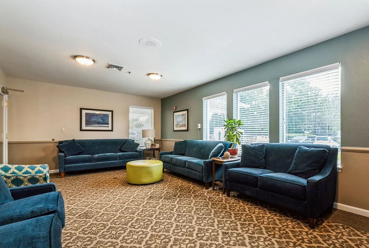 A cozy living room with multiple couches, large windows, and a patterned carpet.