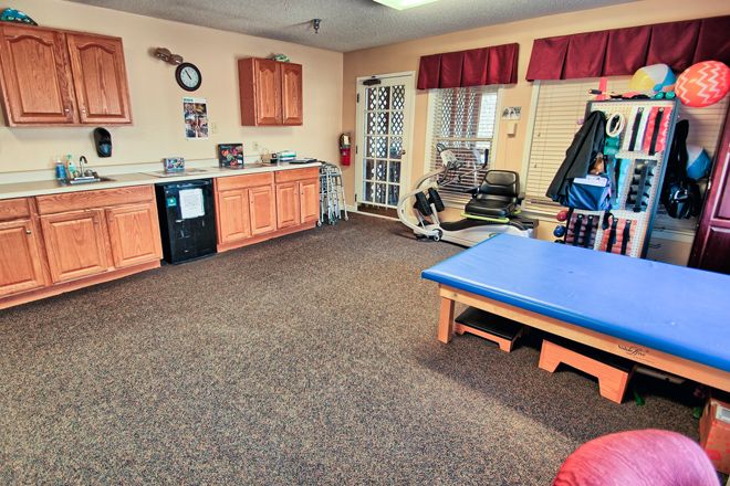 A well-equipped physical therapy room with exercise equipment and treatment tables.
