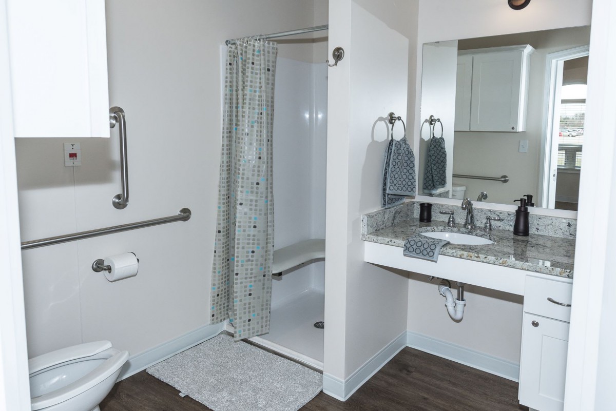 An accessible bathroom with a shower, grab bars, and a sink.