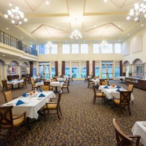 An elegant dining room with neatly arranged tables and chandeliers.