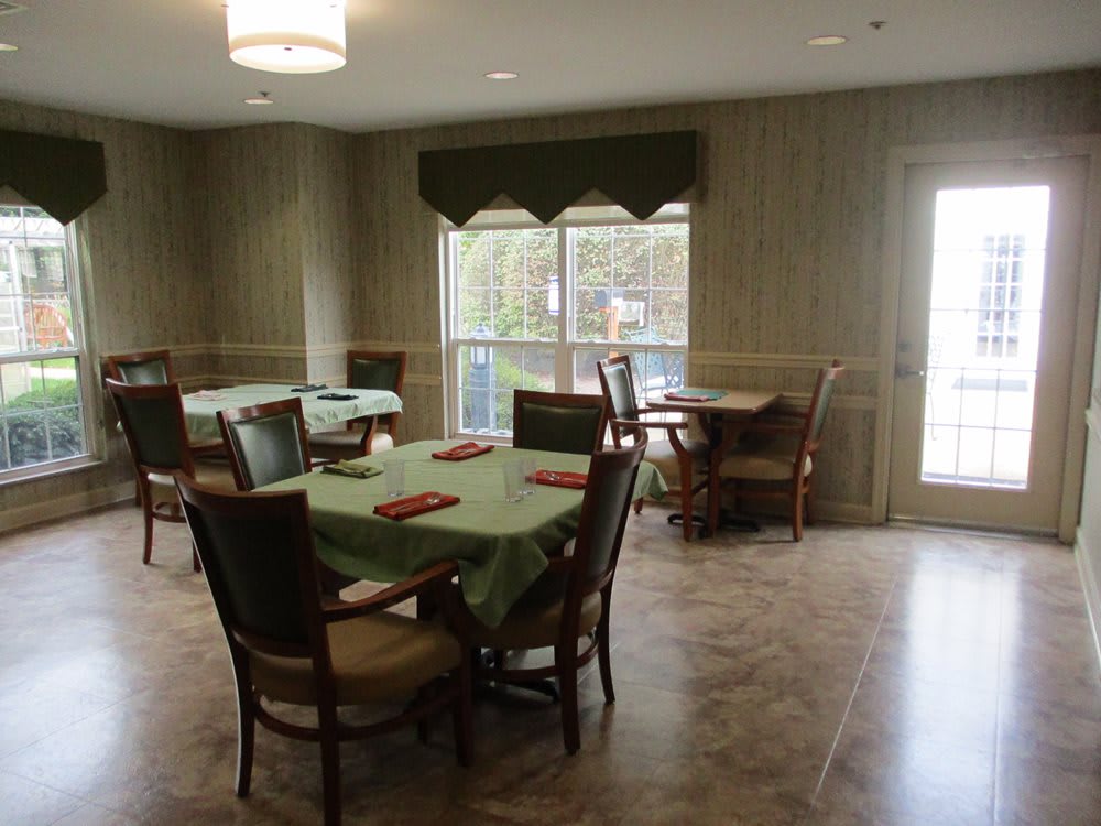 A cozy dining room with neatly arranged tables and chairs near a large window.