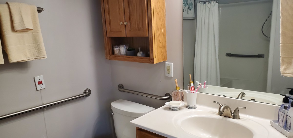 A neatly organized bathroom with a sink, toilet, and wooden cabinet.