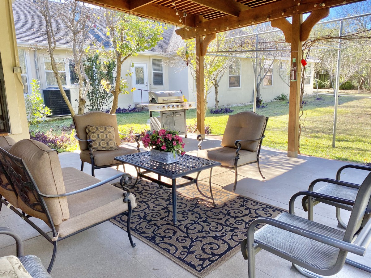 A cozy patio setup with comfortable seating under a pergola, perfect for outdoor relaxation.