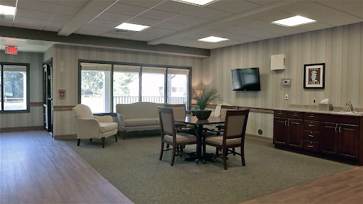 A cozy and welcoming lobby area with comfortable seating and a round table, illuminated by natural light.