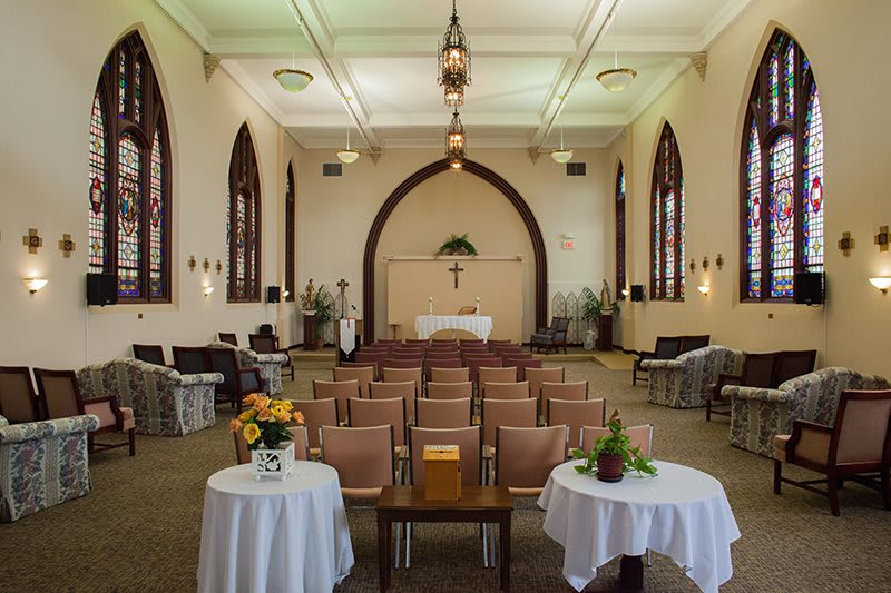 A beautifully decorated chapel set up for a wedding ceremony with an altar and chairs arranged in rows.