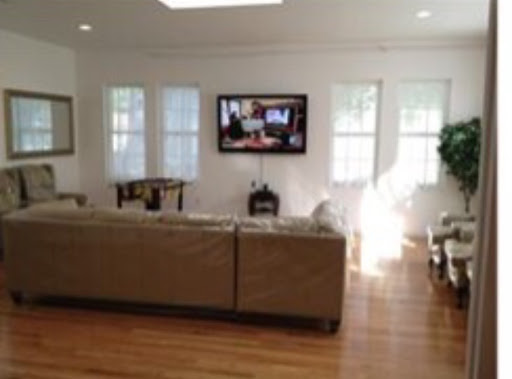 A cozy living room featuring a comfortable sofa and a television, illuminated by natural light.
