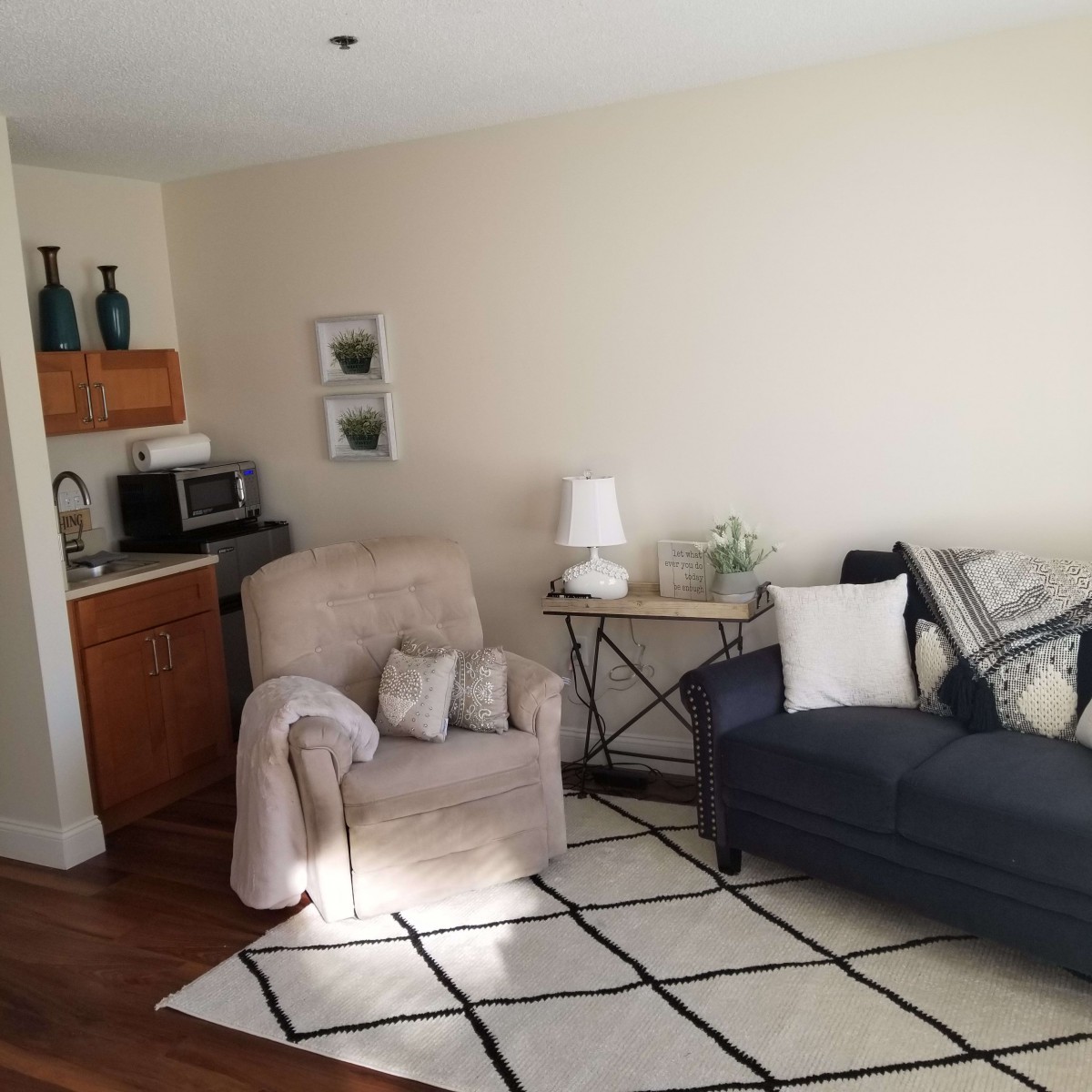 A cozy living room with an armchair, sofa, and a decorative rug.