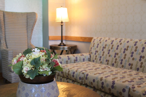 A cozy living room setup featuring a floral couch, a decorative lamp, and a charming flower arrangement.