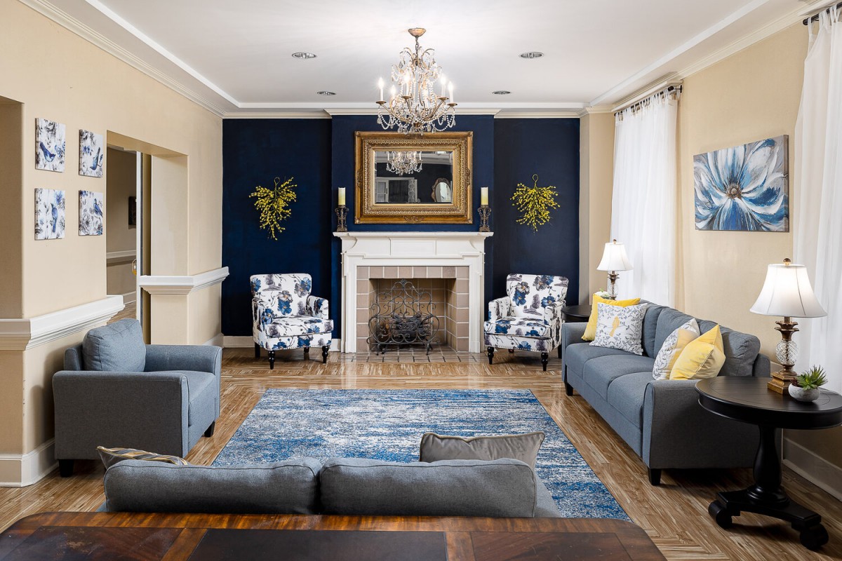 A stylishly decorated living room featuring a fireplace, sofas, armchairs, and a chandelier.