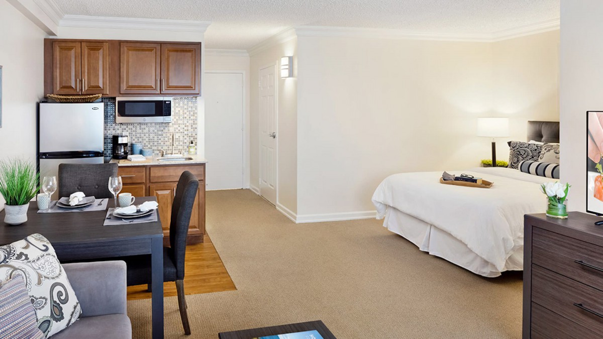 A spacious hotel room featuring a comfortable bed, a kitchenette, and a small dining area.