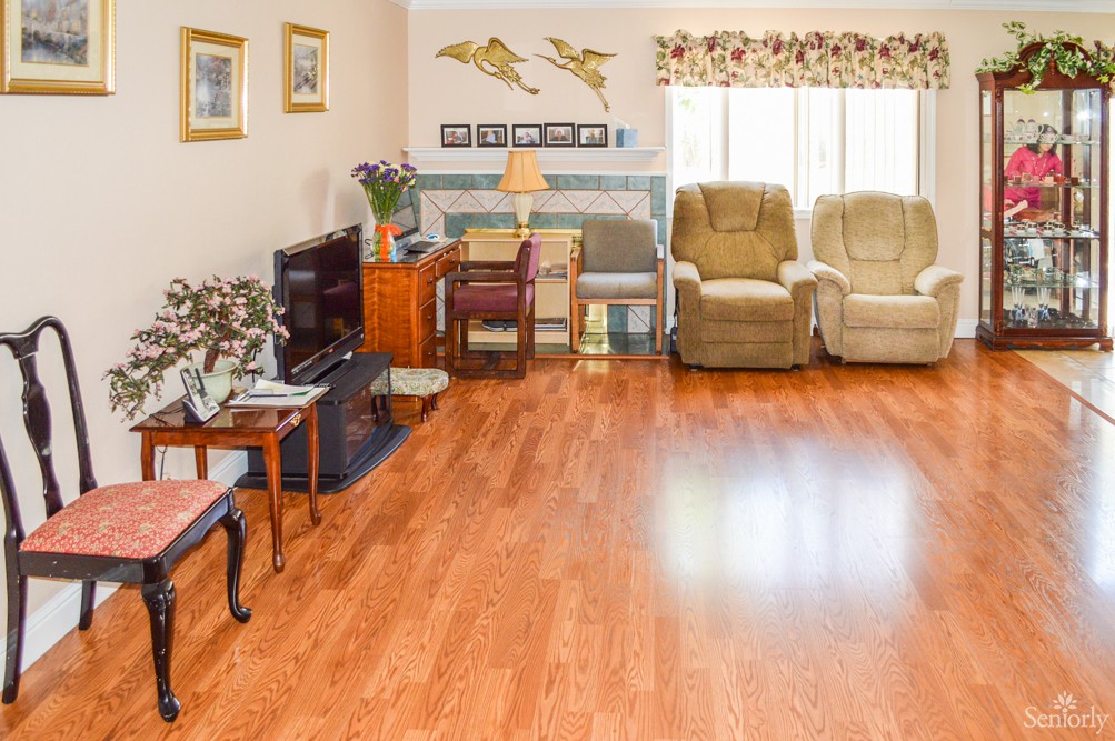 A cozy living room with hardwood floors, featuring recliner chairs, a television, and decorative elements.