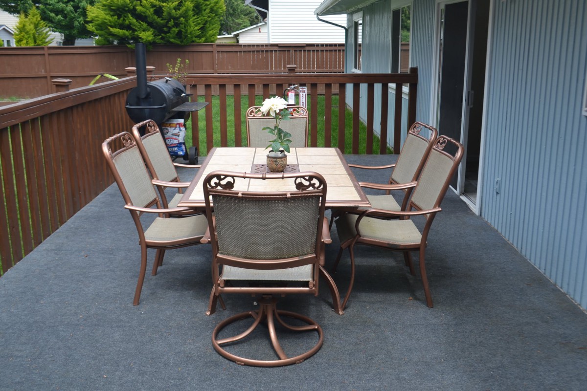 A cozy outdoor patio setup with a table, chairs, and a grill on the deck.