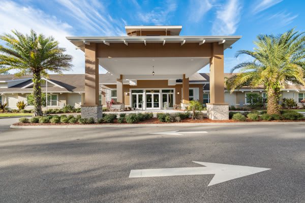 A modern building entrance with a covered driveway and landscaped surroundings.