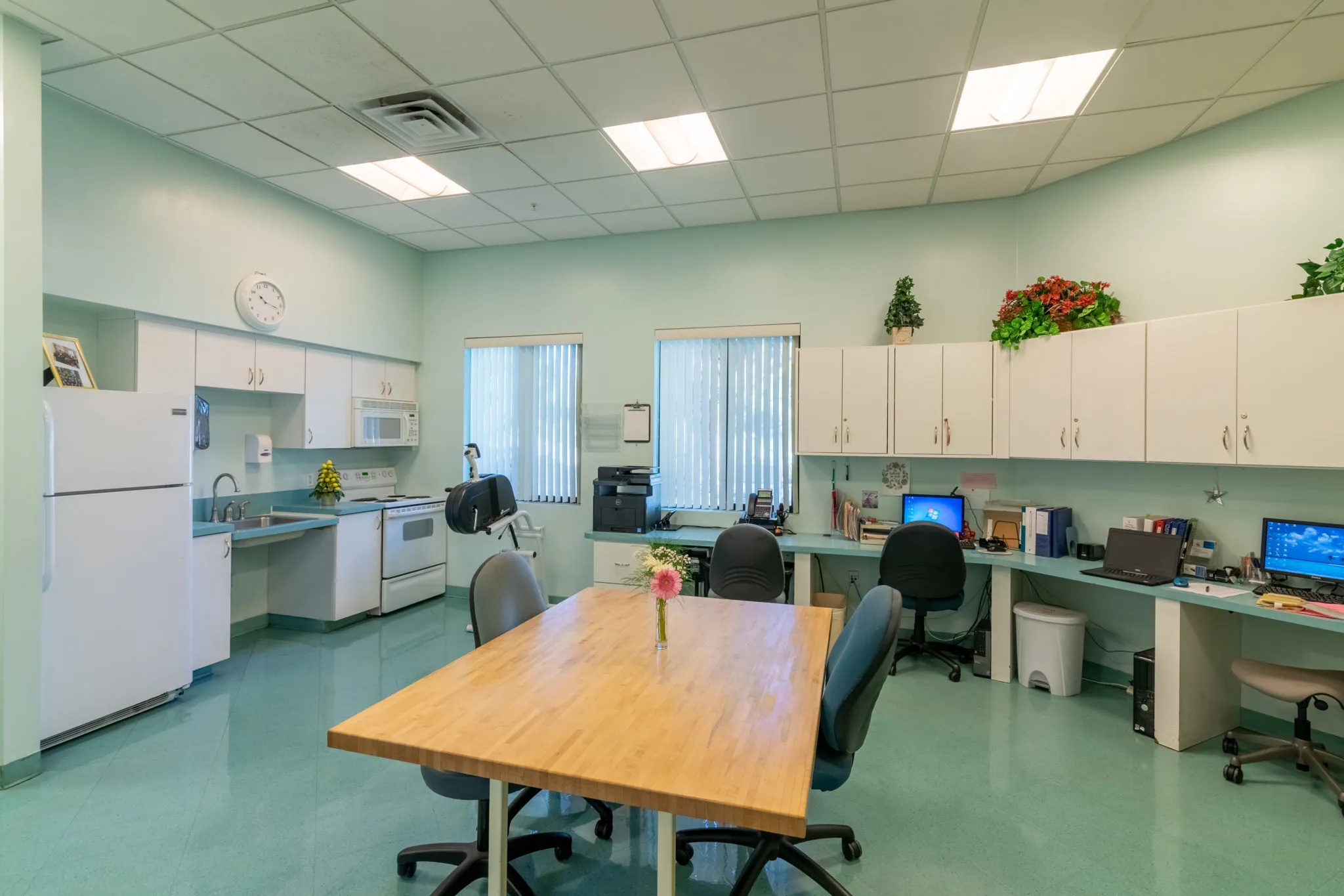 A spacious office area with desks, computers, and a kitchenette.