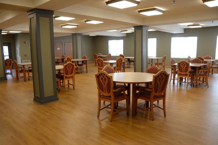 A spacious dining area with wooden tables and chairs, well-lit by overhead lights.