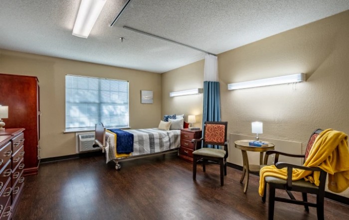 A well-lit hospital room with a patient bed and comfortable seating.