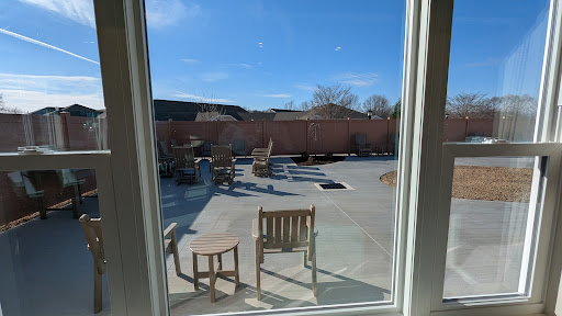 A sunny patio view with wooden chairs and a clear blue sky.