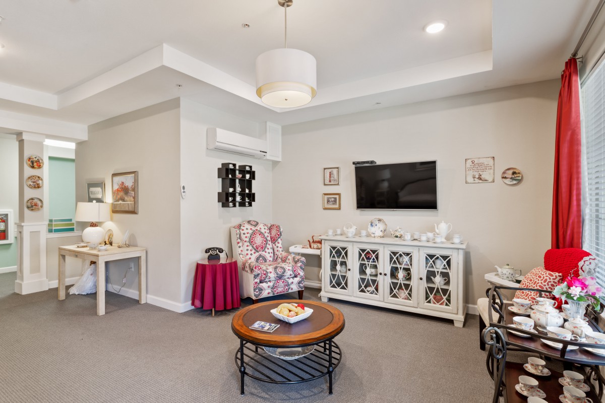 A cozy living room with modern decor, featuring a TV, armchair, coffee table, and stylish wall art.