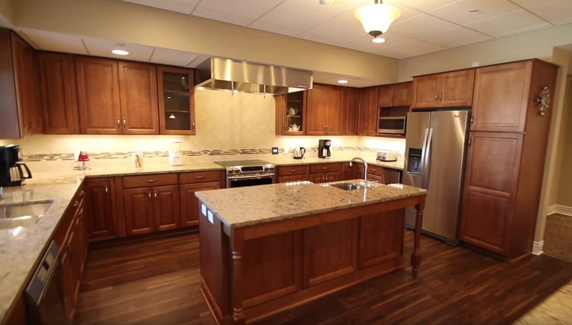 A modern kitchen with wooden cabinets, a central island, and stainless steel appliances.