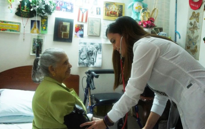 A healthcare professional conducting a checkup on an elderly woman at her home.