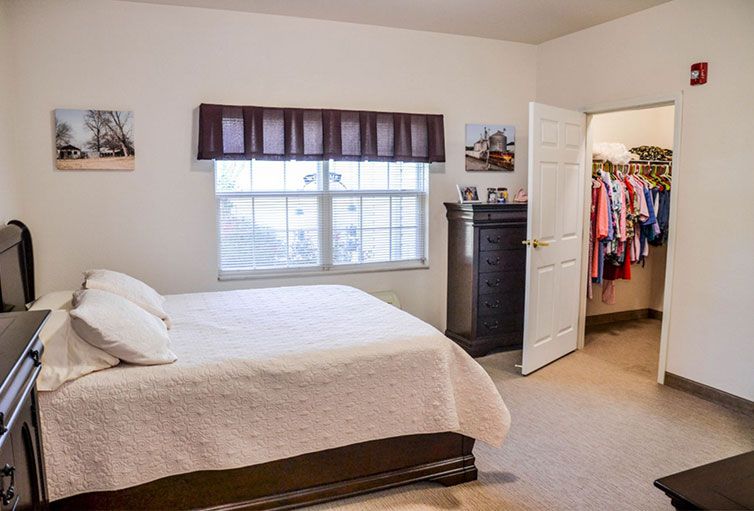 A cozy bedroom with a bed, dresser, and open closet.