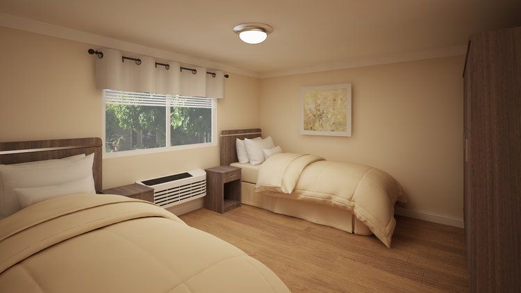 A cozy bedroom with twin beds and simple decor, featuring a window and wood flooring.