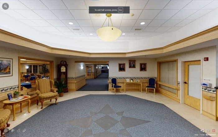 A spacious lobby area with chairs, a chandelier, and a corridor leading further inside.