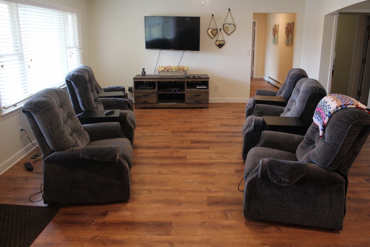 A cozy living room with multiple recliners facing a wall-mounted TV and entertainment center.