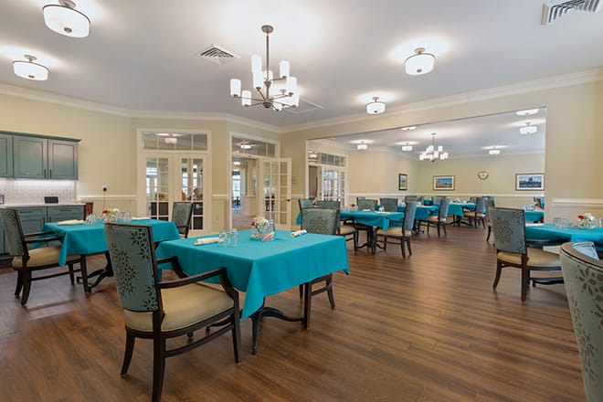 An elegant dining room with turquoise tablecloths and chandeliers.