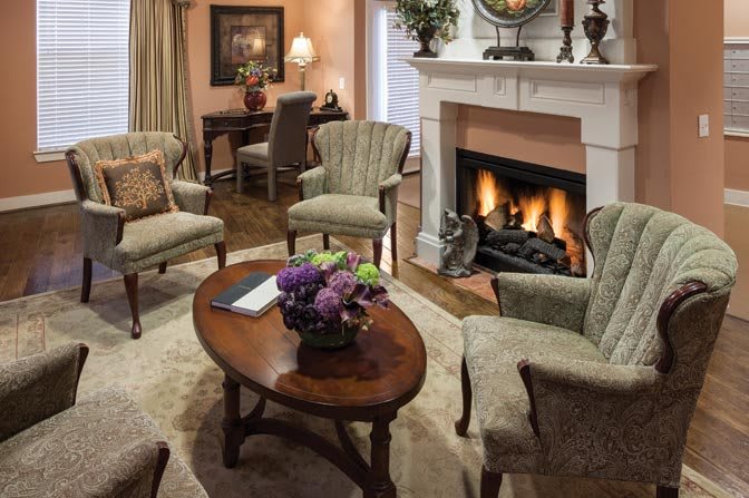 A cozy living room with a fireplace, comfortable chairs, and elegant decor.