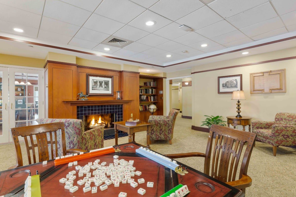A cozy living room with a fireplace, game table, and comfortable seating.