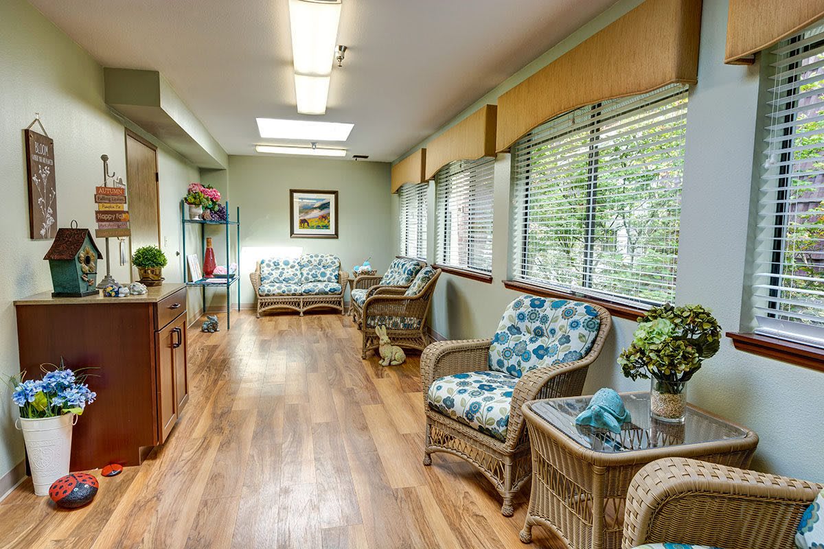A bright hallway with wicker seating and large windows overlooking greenery.