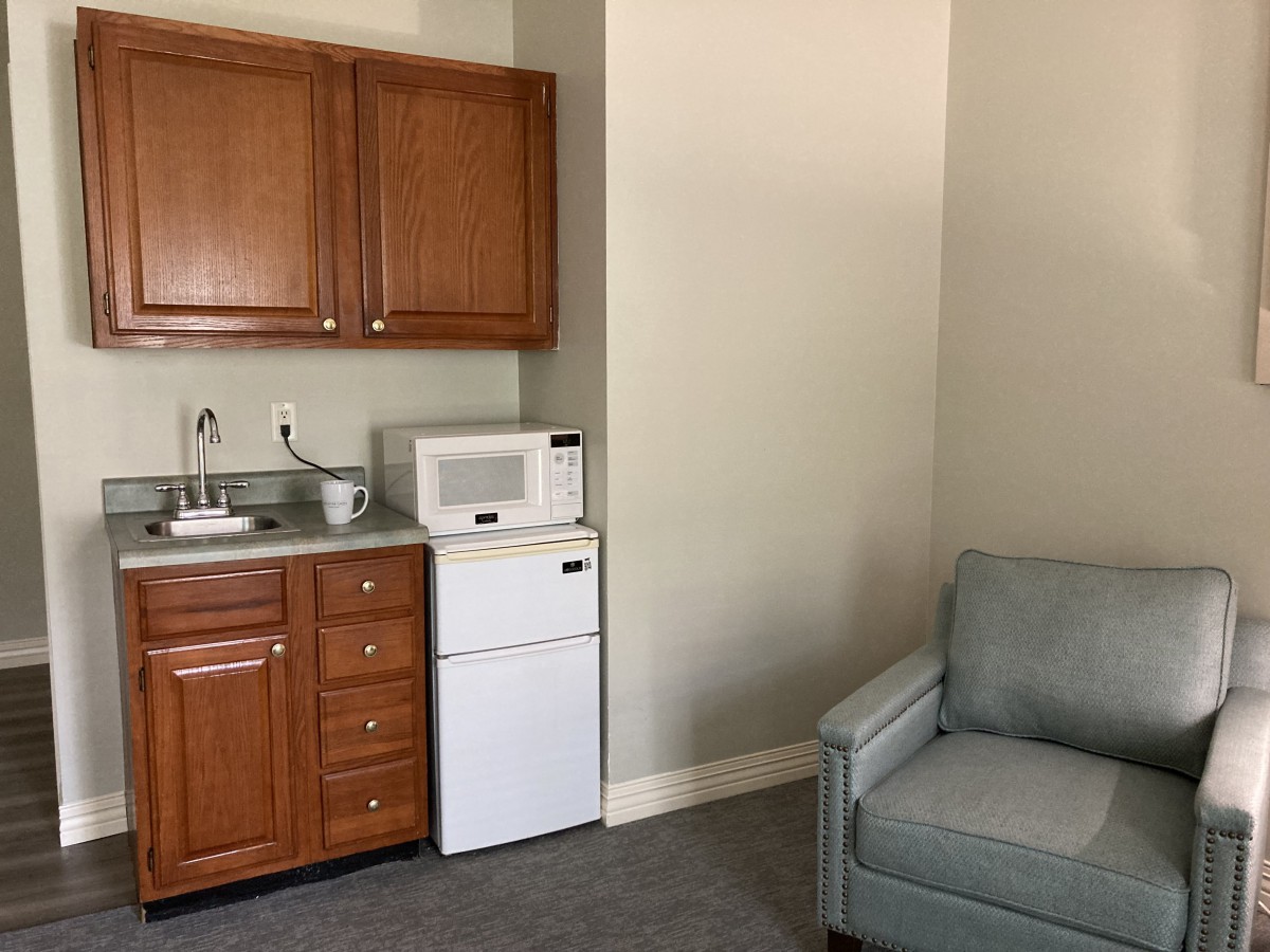 A cozy kitchenette with a microwave and small fridge adjacent to an armchair.