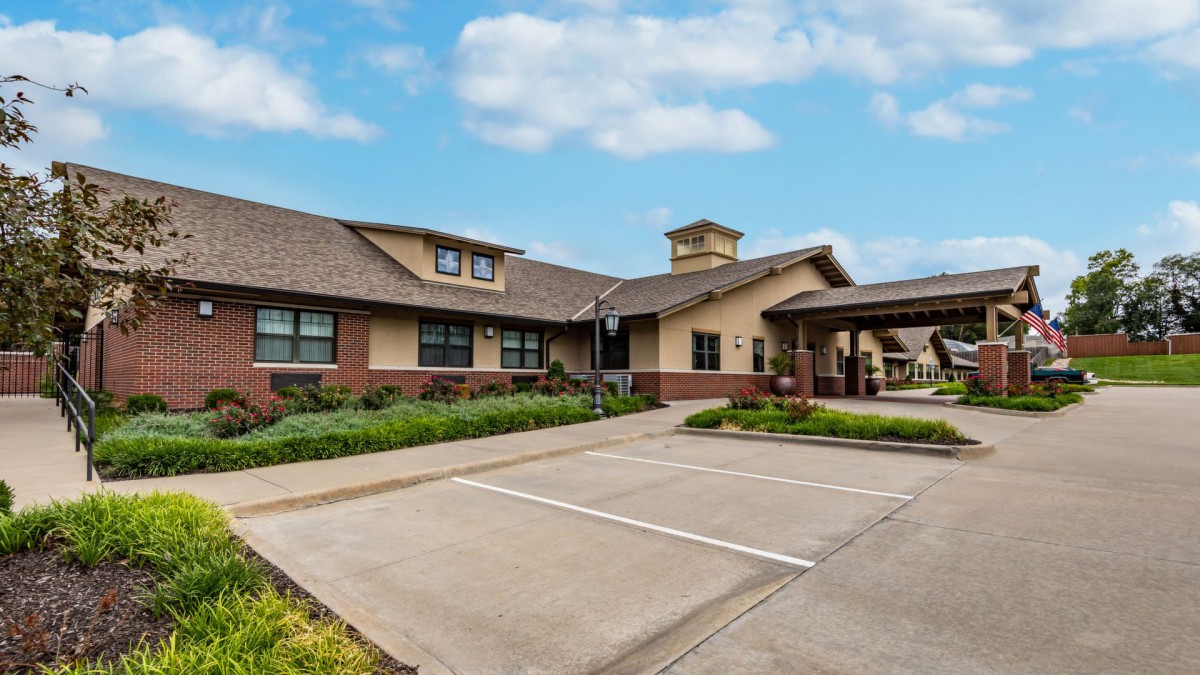 A residential-style building with a parking lot under a blue sky with clouds.