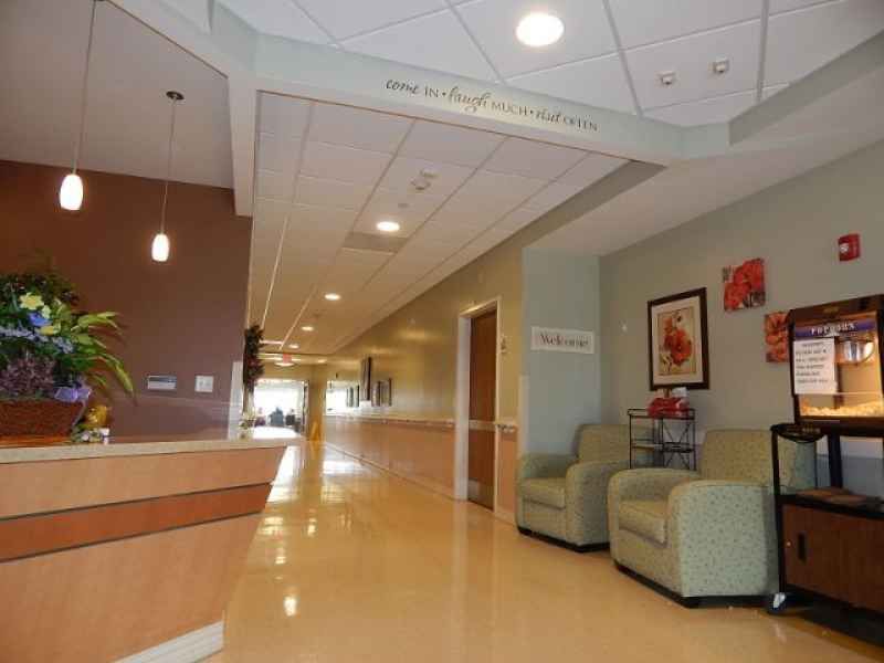 A hospital lobby with a reception desk, seating area, and hallway.