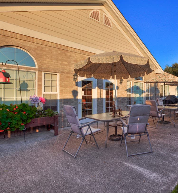 A cozy outdoor patio area with tables, chairs, and umbrellas adjacent to a building.