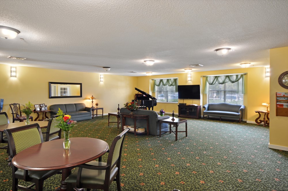 A spacious living room with a piano, sofas, and a television.