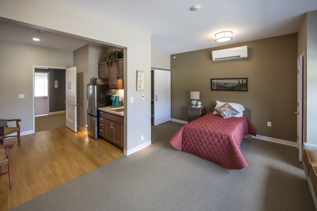 A cozy studio apartment with an integrated kitchenette and a comfortable bed.