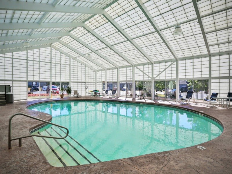 A spacious indoor swimming pool with a glass-paneled ceiling.