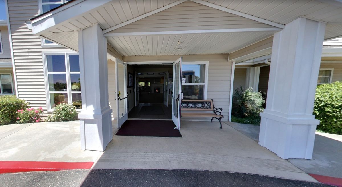 A view of a building entrance with a porch and bench.