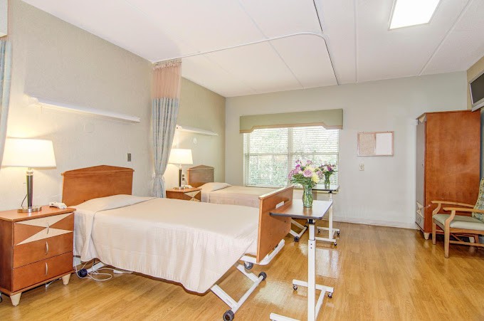 An empty hospital room with two beds and a window, providing a clean and calming environment for patient care.