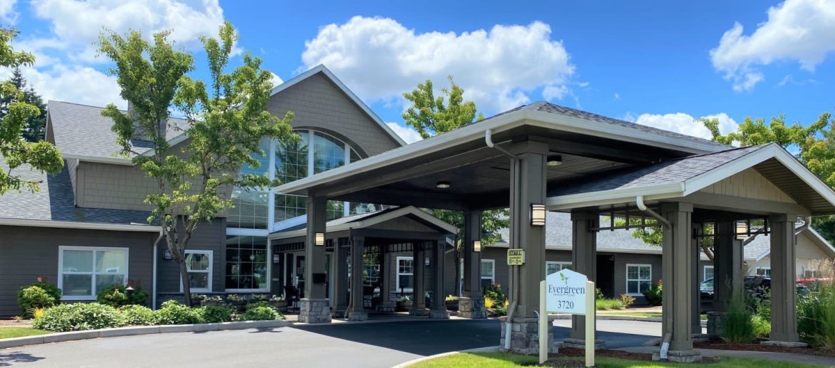 A modern building entrance under a clear blue sky with clouds.