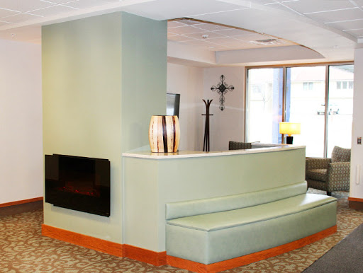 A modern lobby featuring green walls, a unique seating area, and a cozy fireplace.
