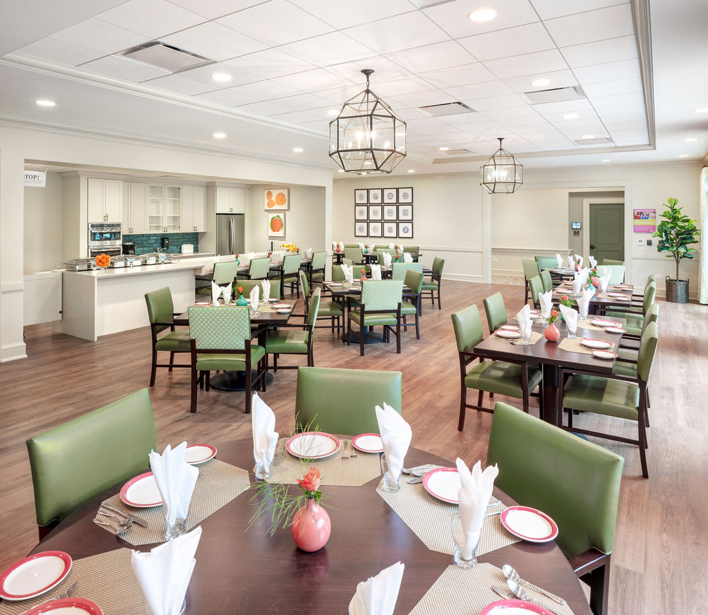 A well-lit dining room with neatly arranged tables and chairs, featuring elegant table settings.
