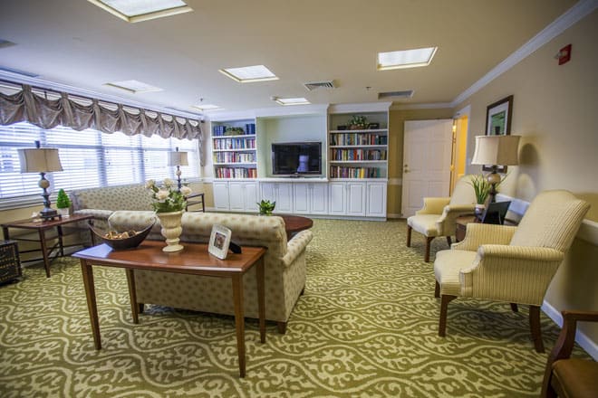 A cozy living room with a sofa, chairs, bookshelves, and a television.