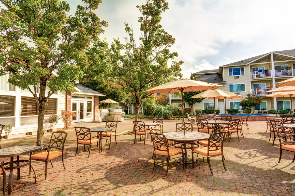 A charming outdoor patio with tables and umbrellas set amidst a scenic setting.
