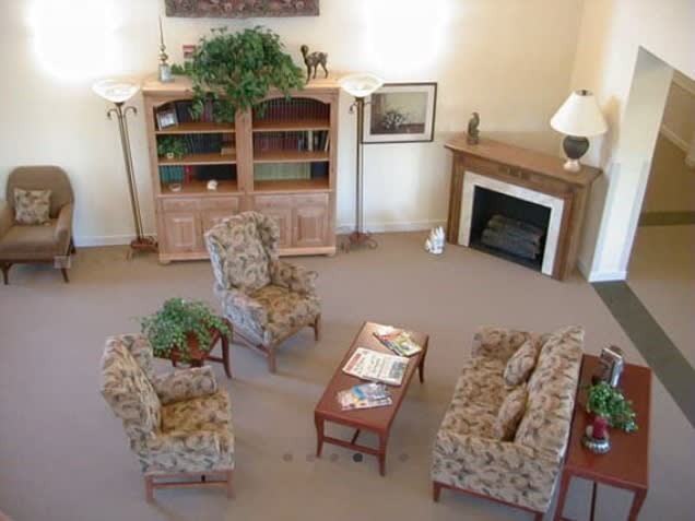 A well-furnished living room with a sofa, chairs, coffee table, bookshelf, and fireplace.